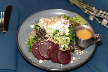 Sliced roasted beets with mixed greens, goat cheese and sunflower seeds, and a jug of vinaigrette