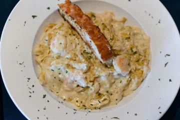Shrimp in a cream sauce over fettuccine, parsley through it, with a slice of garlic bread
